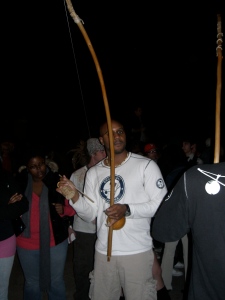A performer plays the berimbau for Capoeira dancers.